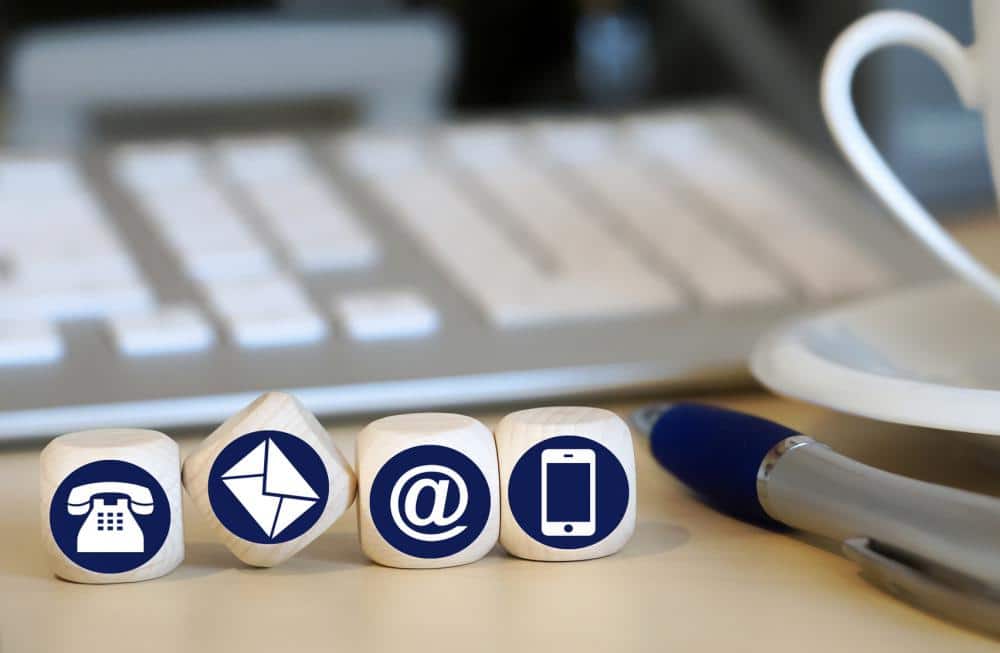 Würfel mit Kontaktsymbolen vor Tastatur